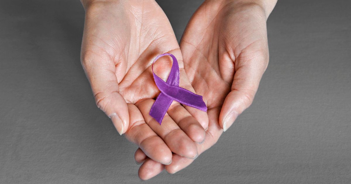 Hände, die eine lila Krebsschleife halten