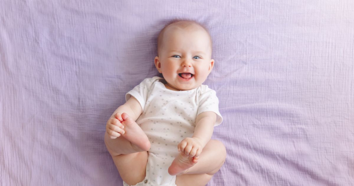 Lachendes Baby, das auf dem Rücken liegt und seine Füße greift