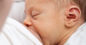 Baby ist an der Brust der mama angelegt.
