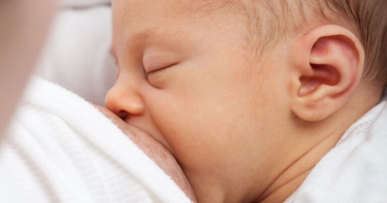 Baby ist an der Brust der mama angelegt.