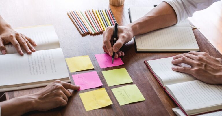 Tisch mit Heften, Büchern, Stiften und Post-its