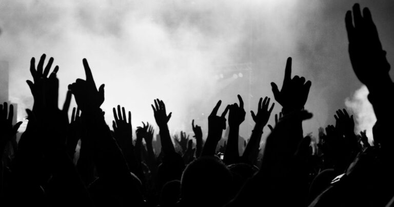 Schwarz-weiß Fotografie von einem Publikum bei einem Konzert. Hände nach oben ausgestreckt