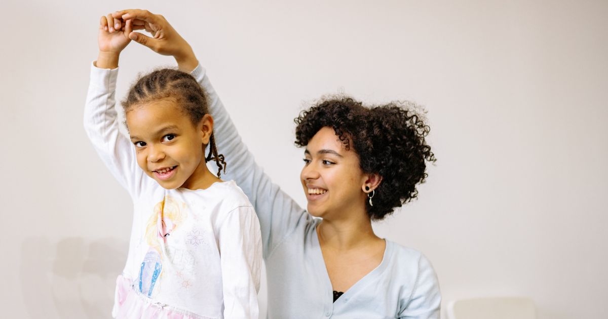 Kind tanzt mit weiblich gelesener, erwachsener Person