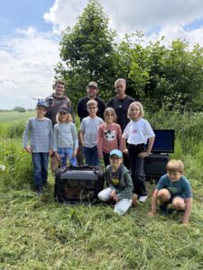 Kinder der Grundschulkindbetreuung Flottkamp auf einem Feld mit Equipment für die Rehkitzrettung.