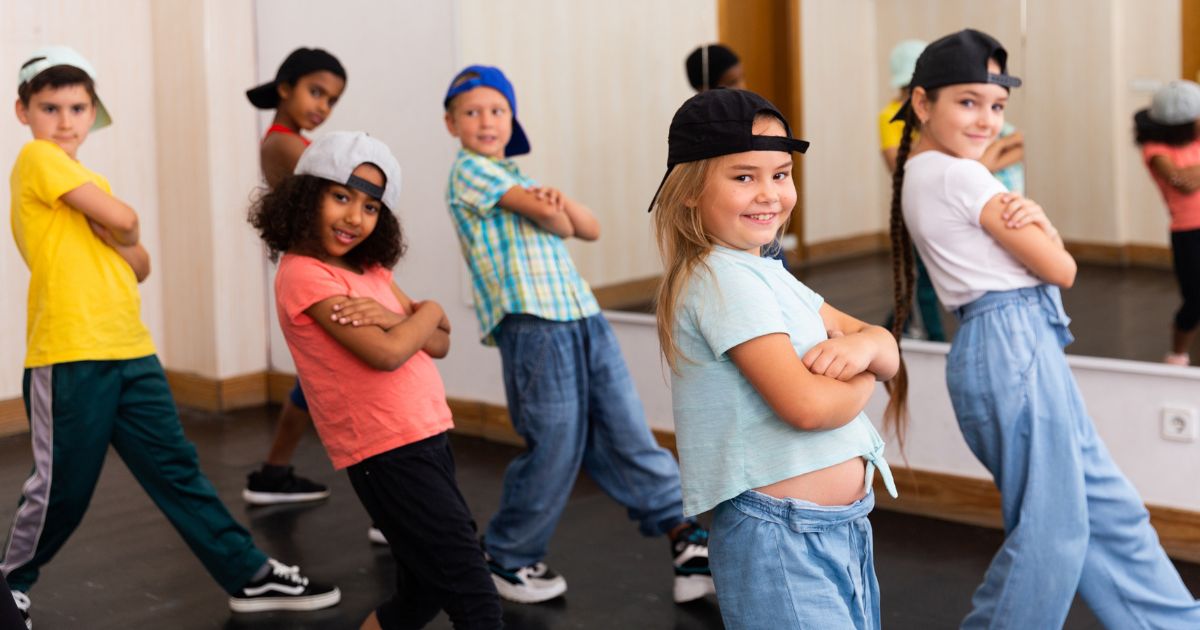 Kinder in einem Raum mit Spiegel stehen in einer tänzerischen Pose